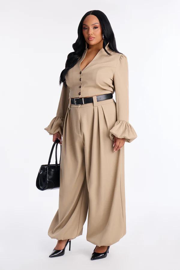 Elegante mujer con conjunto de dos piezas camel: top corto, mangas campana y pantalones anchos, cinturón negro. Nueva moda femenina.
