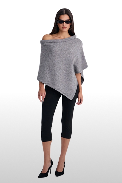 Woman in a grey off-the-shoulder knit poncho sweater, black cropped leggings, and high heels.