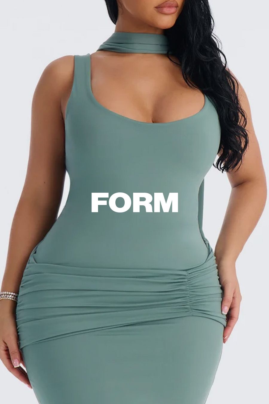 Curvy model wears a sage green FORM brand ruched bodycon dress with a matching choker, showcasing the brand's new form-fitting collection.