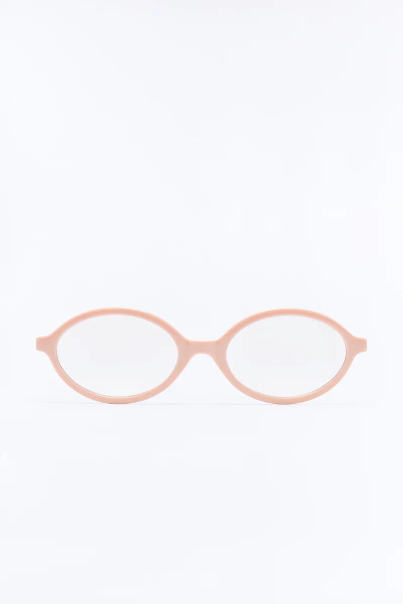 Monturas de gafas ovaladas en color rosa pastel sobre fondo blanco, destacando el diseño de lentes modernos para un catálogo de moda.