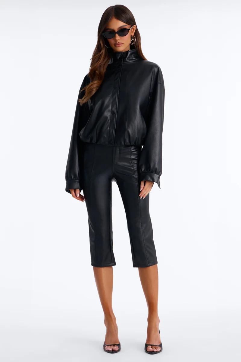 Woman wearing a chic black faux leather bomber jacket and matching cropped capri pants for a modern, edgy autumn fashion collection look.
