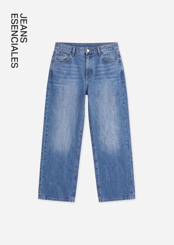 Jeans vaqueros azules de tiro alto y pernera recta en lavado medio de la colección Denim Essentials, sobre un fondo gris claro.