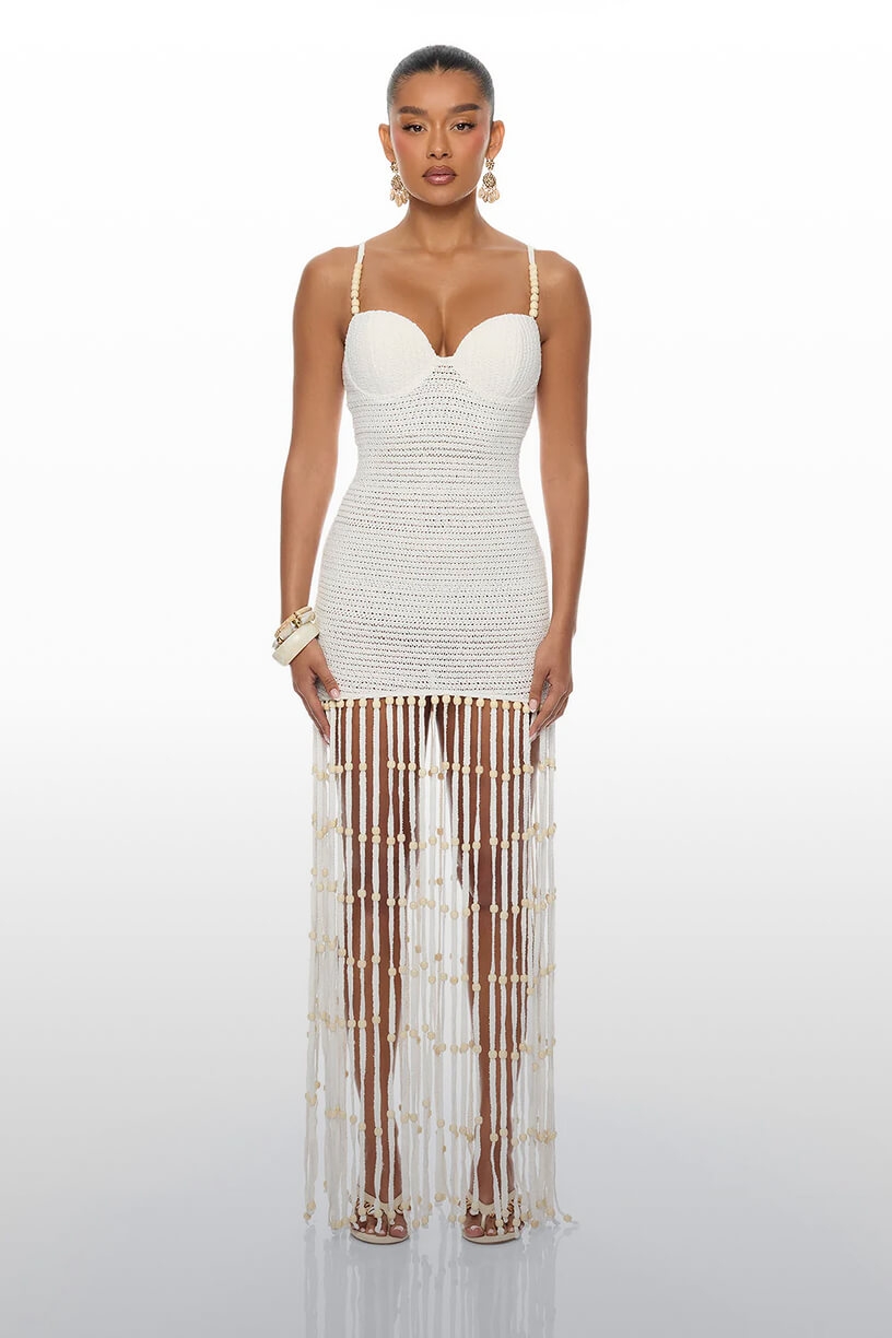 Modelo luciendo un vestido bustier blanco de crochet con tirantes finos y flecos largos con cuentas. Compra estilos nuevos.