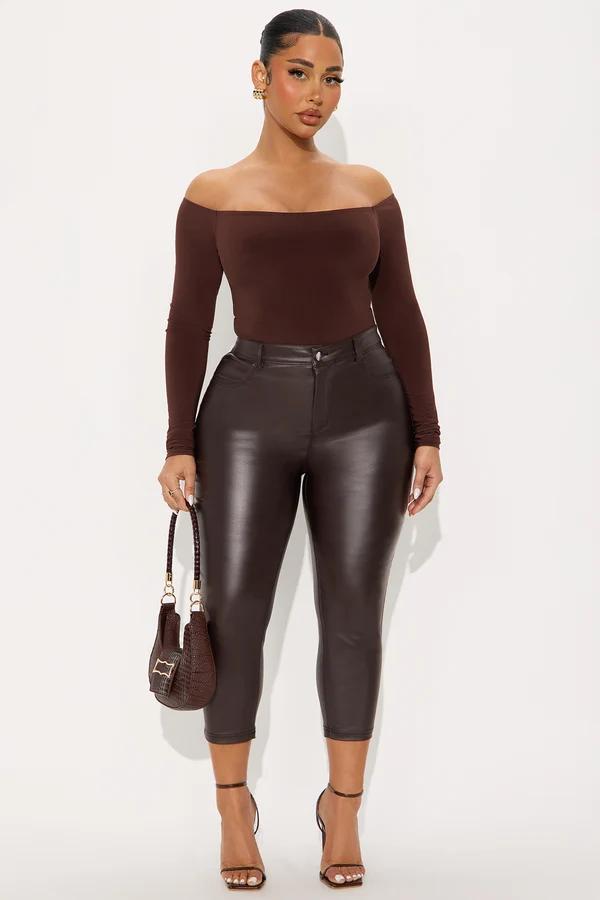 Model wearing a brown off-the-shoulder top and high-waisted faux leather pants, showcasing chic monochrome women's autumn fashion.