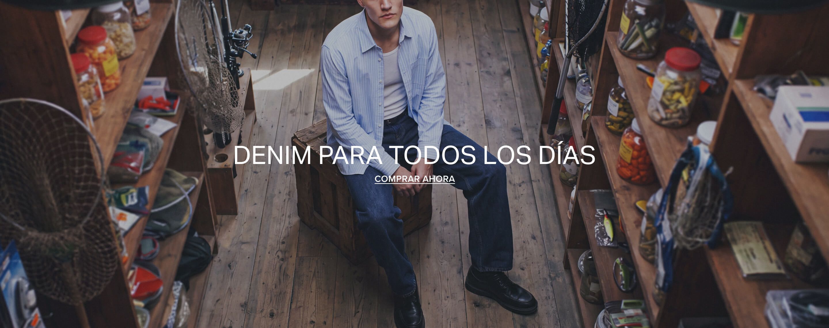 Hombre con camisa azul rayas, camiseta blanca y vaqueros denim azul oscuro sobre caja. Promueve moda casual masculina. ¡Compra ahora!