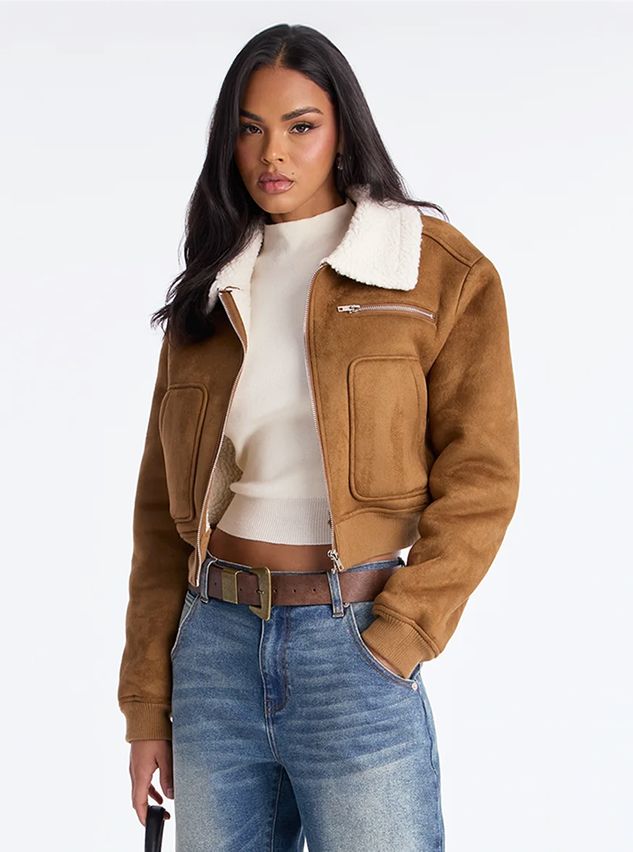 Woman wearing a cropped brown faux suede aviator jacket with white shearling collar, styled with blue jeans for a trendy autumn look.