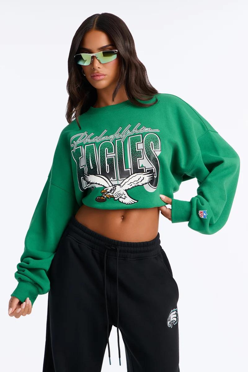 Modelo con sudadera corta verde de los Philadelphia Eagles, joggers negros y gafas de sol.