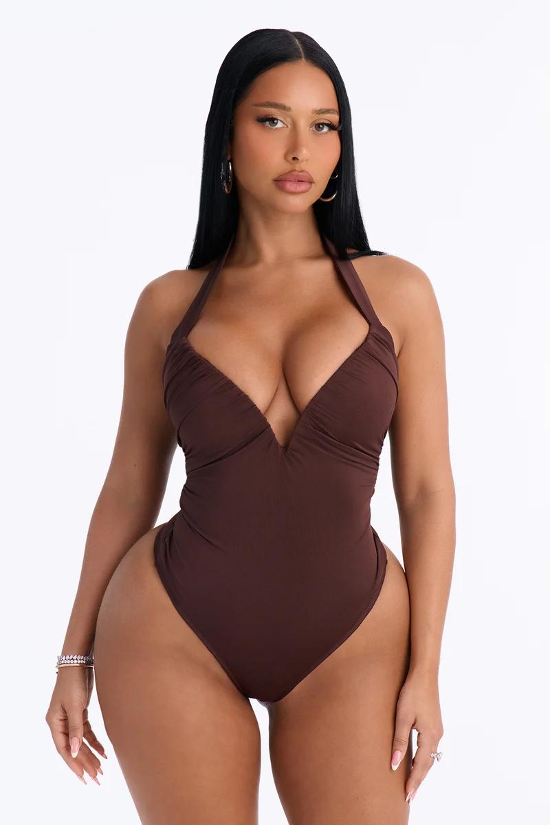 Modelo con un body marrón de cuello halter y escote en V pronunciado.