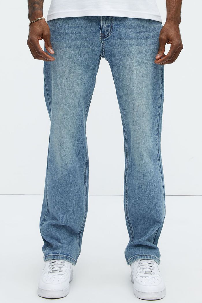 Man wearing men's straight leg jeans in a light blue wash paired with white sneakers, showcasing a new casual streetwear denim collection.