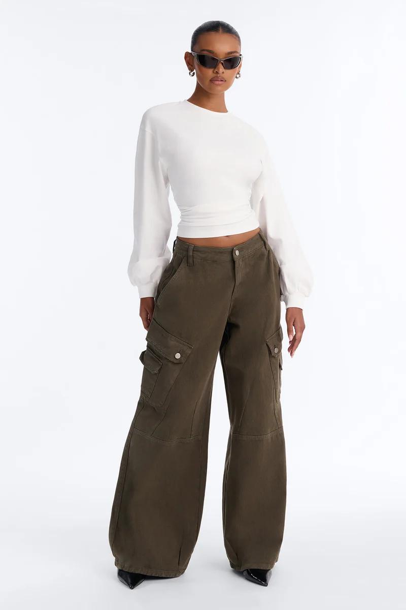 Woman wearing a white long-sleeve crop top and olive green wide-leg cargo pants with sunglasses.