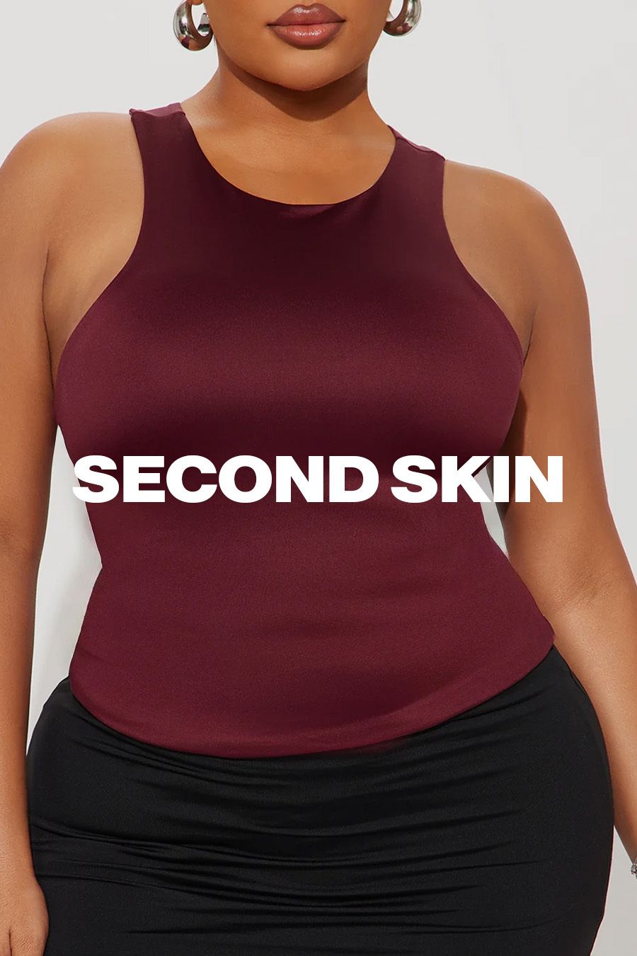 Mujer de talla grande modelando top "segunda piel" burdeos y falda negra. Destaca la comodidad y ajuste elegante de la ropa.