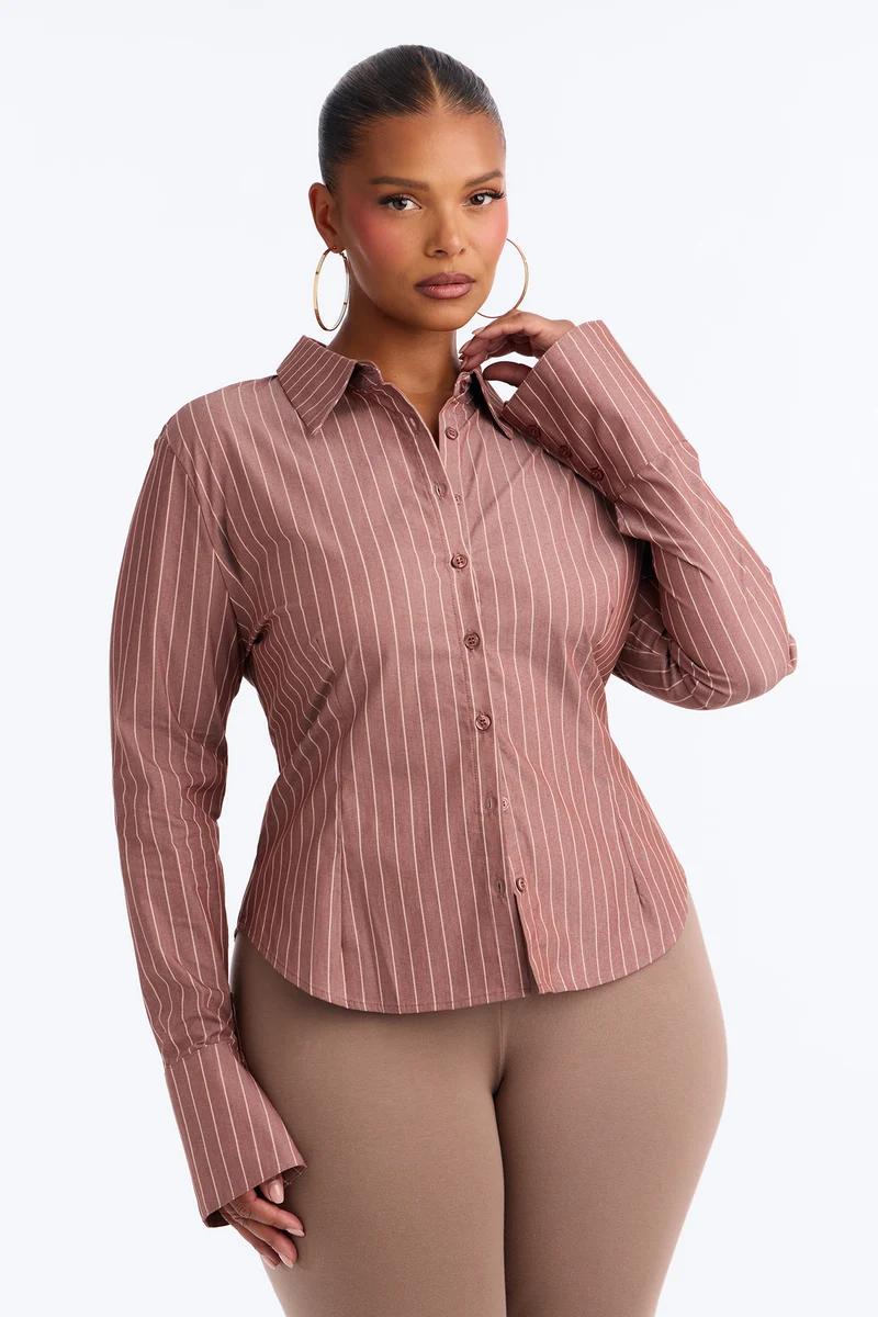Woman wearing a dusty rose and white pinstripe long-sleeve button-down shirt.