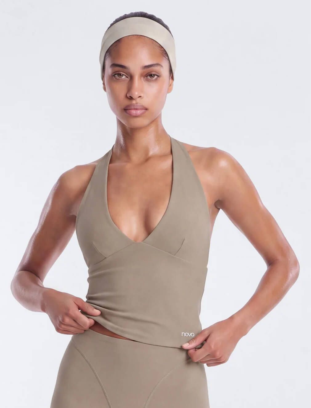 Model wearing a Nova beige halter neck activewear tank top and matching headband, showcasing the new athletic wear collection.