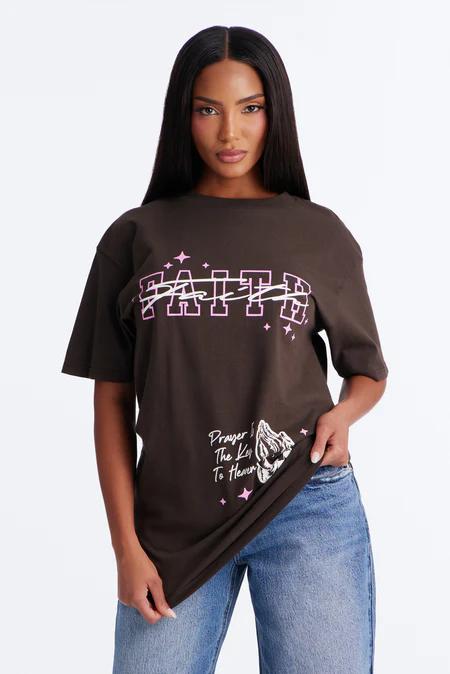 Woman models a dark brown graphic tee featuring "FAITH" and "Prayer The Key To Heaven" with praying hands. Shop new faith apparel for women.
