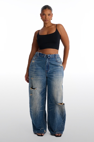 Stylish woman models a black spaghetti strap crop top and light wash distressed wide-leg baggy jeans, showcasing a comfortable, trendy style.