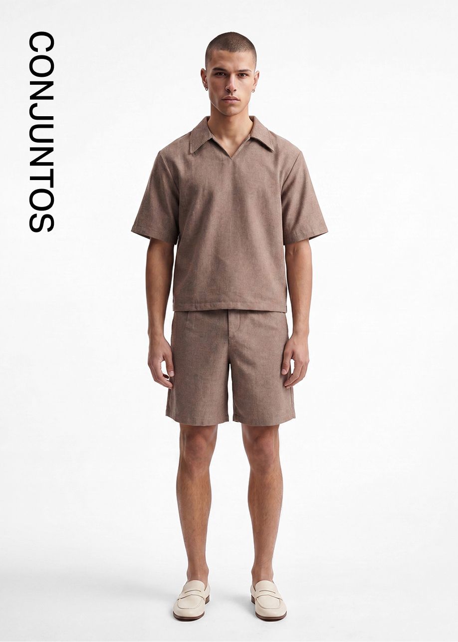 Modelo masculino en conjunto marrón de camisa de manga corta y shorts, con mocasines crema. Promueve conjuntos a juego casuales para hombres.