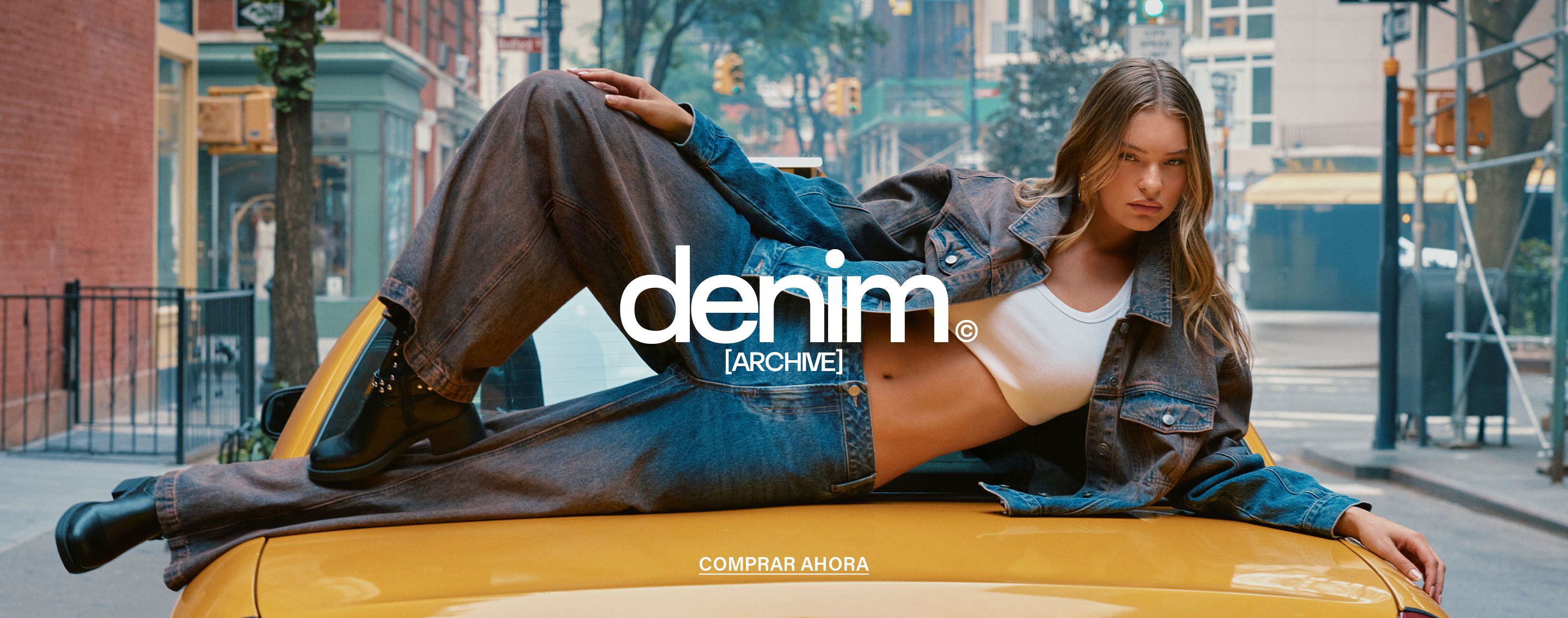 Mujer posa sobre un taxi amarillo vistiendo una chaqueta vaquera extragrande y jeans, promocionando la nueva colección Denim Archive.