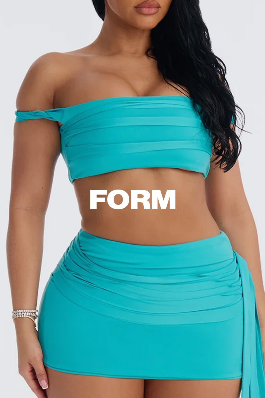 Stylish woman in a vibrant teal off-shoulder ruched crop top and matching mini skirt, with "FORM" text. Promotes new fashion collection.