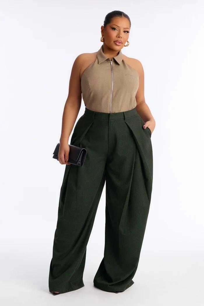 Plus-size model wearing a beige zip halter top and dark green wide-leg pleated trousers.