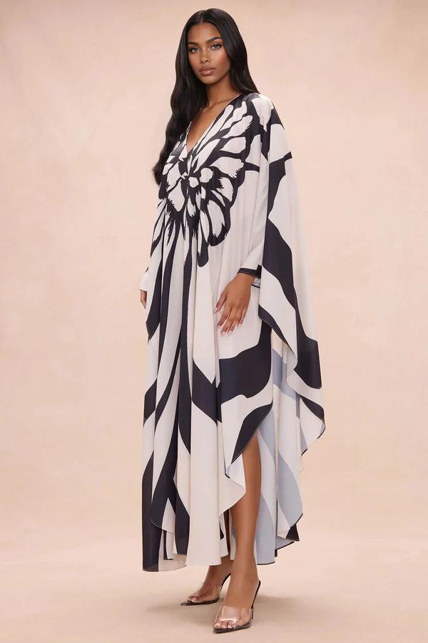 Woman in a flowing black and white butterfly print V-neck kaftan dress with long sleeves and sheer heels, showcasing a new elegant resort wear collection.
