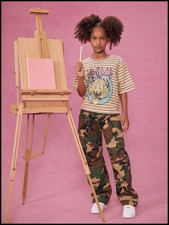 Young girl models a cute pink striped short-sleeve shirt with a white pleated skirt. Perfect kids' fashion for summer outfits.