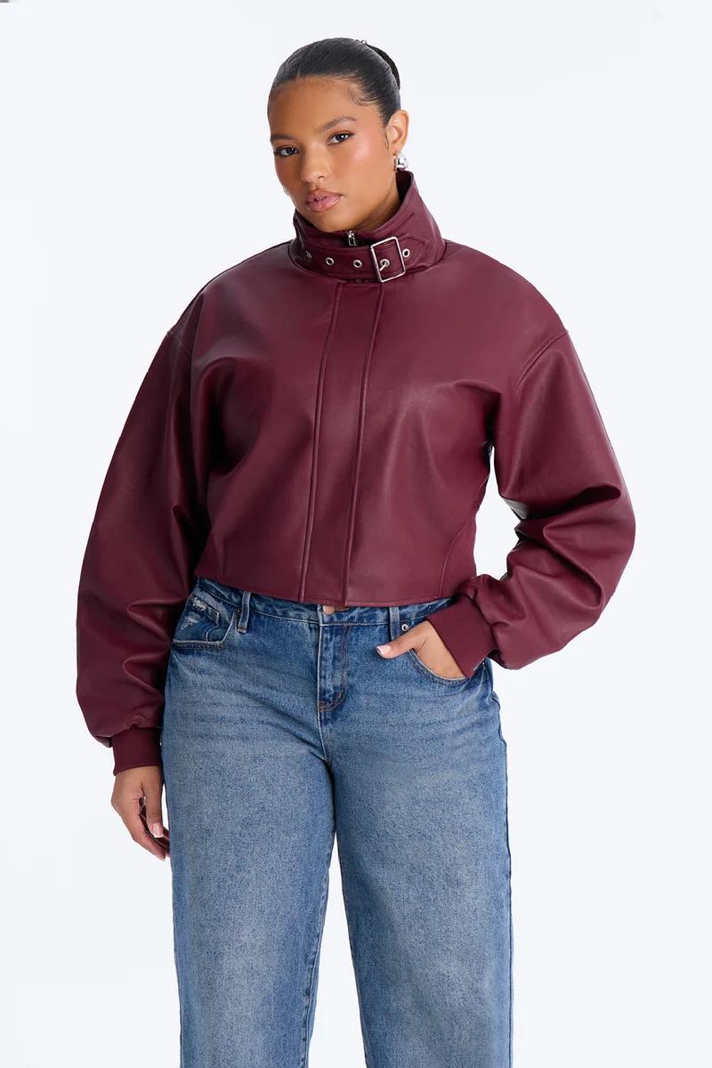 Modelo de talla grande con cazadora corta de cuero sintético burdeos y vaqueros.