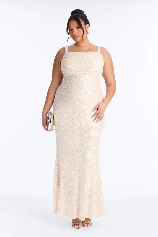 Plus-size model in an elegant, shimmering champagne sequin formal maxi dress with square neckline, holding a metallic clutch.