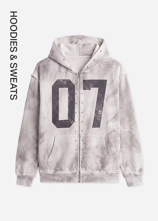 Grey tie-dye zip-up hoodie featuring a distressed 07 graphic and metallic studs, promoting the trendy hoodies and sweats streetwear collection.