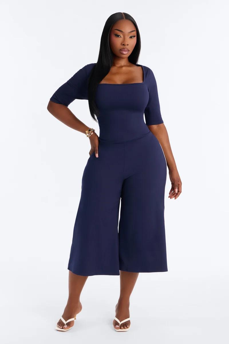 Elegante enterizo azul marino de pierna ancha con escote cuadrado, ideal para promocionar la nueva colección de moda femenina.