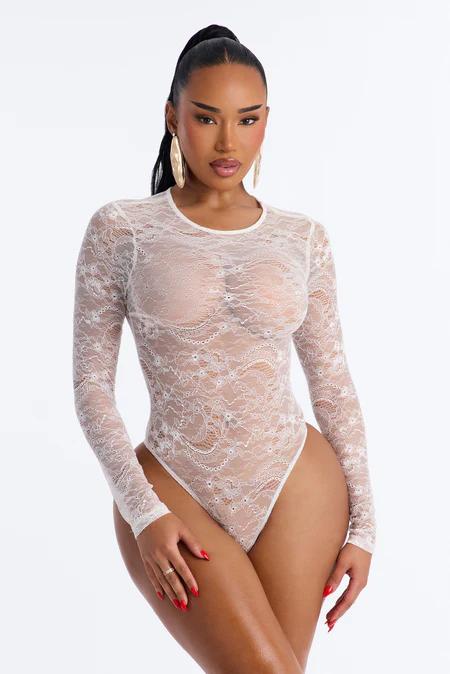 Mujer con coleta oscura en un body floral transparente verde menta de manga larga con flores rosas, posando sobre fondo blanco.