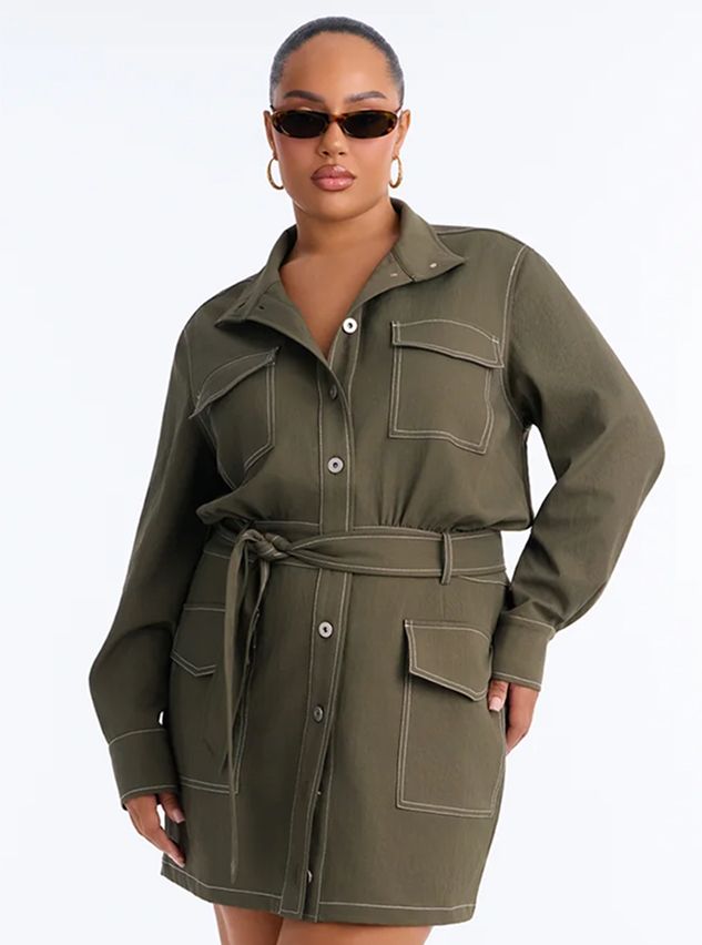 Plus size model wearing an olive green utility shirt dress with white contrast stitching and tie belt.