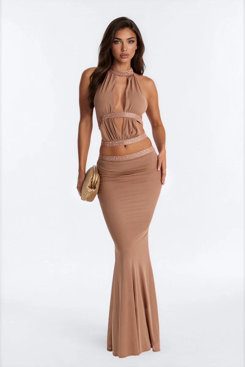 Model in a tan halter cutout crop top and matching mermaid maxi skirt with rhinestone details for the new formal evening wear collection.