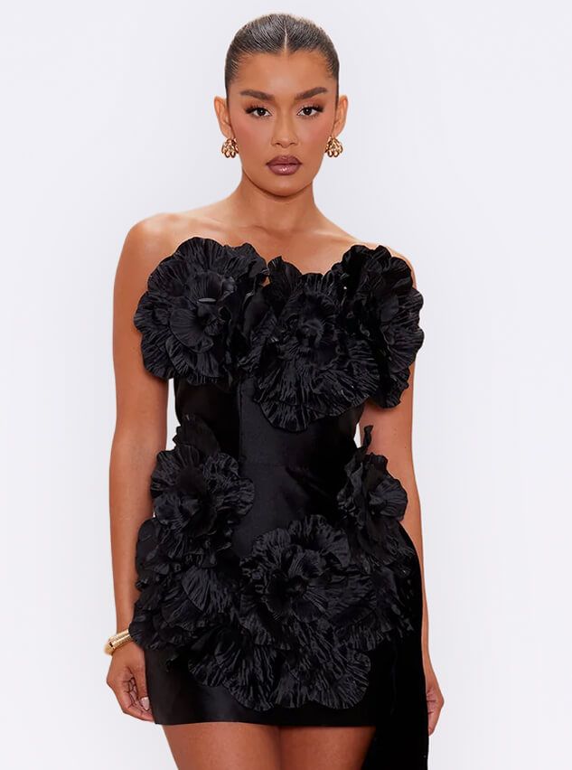 Elegant model in a chic black strapless mini dress with 3D floral ruffle details, promoting the new collection of party dresses.