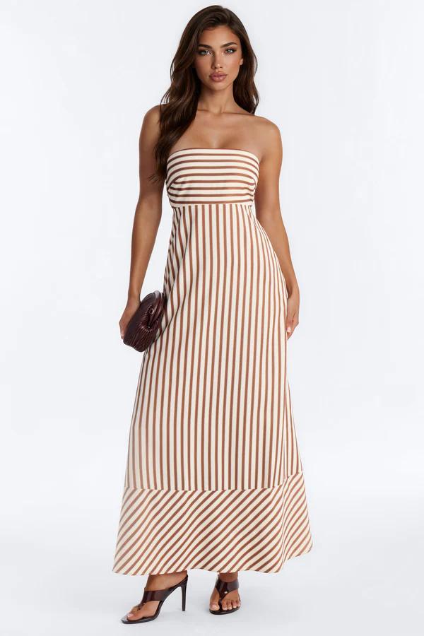 Woman wearing a stylish brown and beige striped strapless maxi dress with a clutch, highlighting elegant summer fashion.