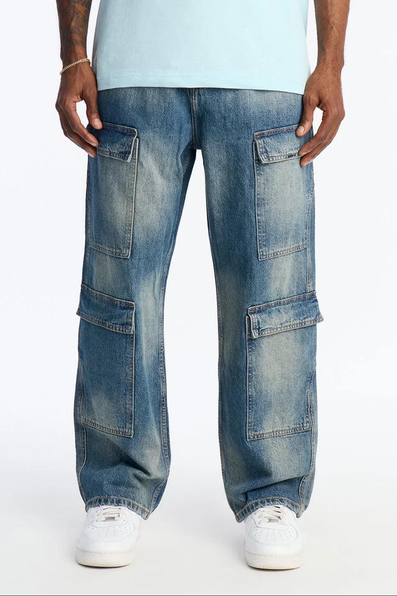 Jeans cargo azules descoloridos de corte holgado con bolsillos, combinados con camiseta celeste y zapatillas blancas. Estilo moda urbana.