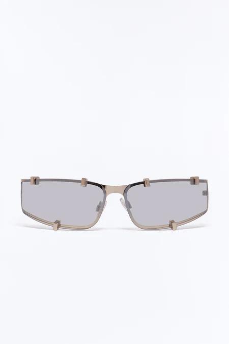 Gafas de sol rectangulares modernas champán-dorado con lentes grises y distintivos acentos de clip, centradas sobre un fondo blanco.