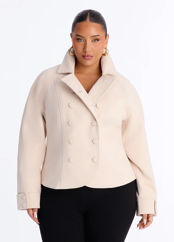 Plus size model wears a chic beige cropped double-breasted jacket with a high collar, promoting the brand's stylish new outerwear line.