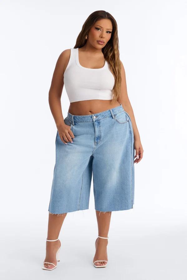 Modelo de talla grande con top corto blanco y shorts de mezclilla holgados de tiro alto, ideal para una colección de moda casual de verano.
