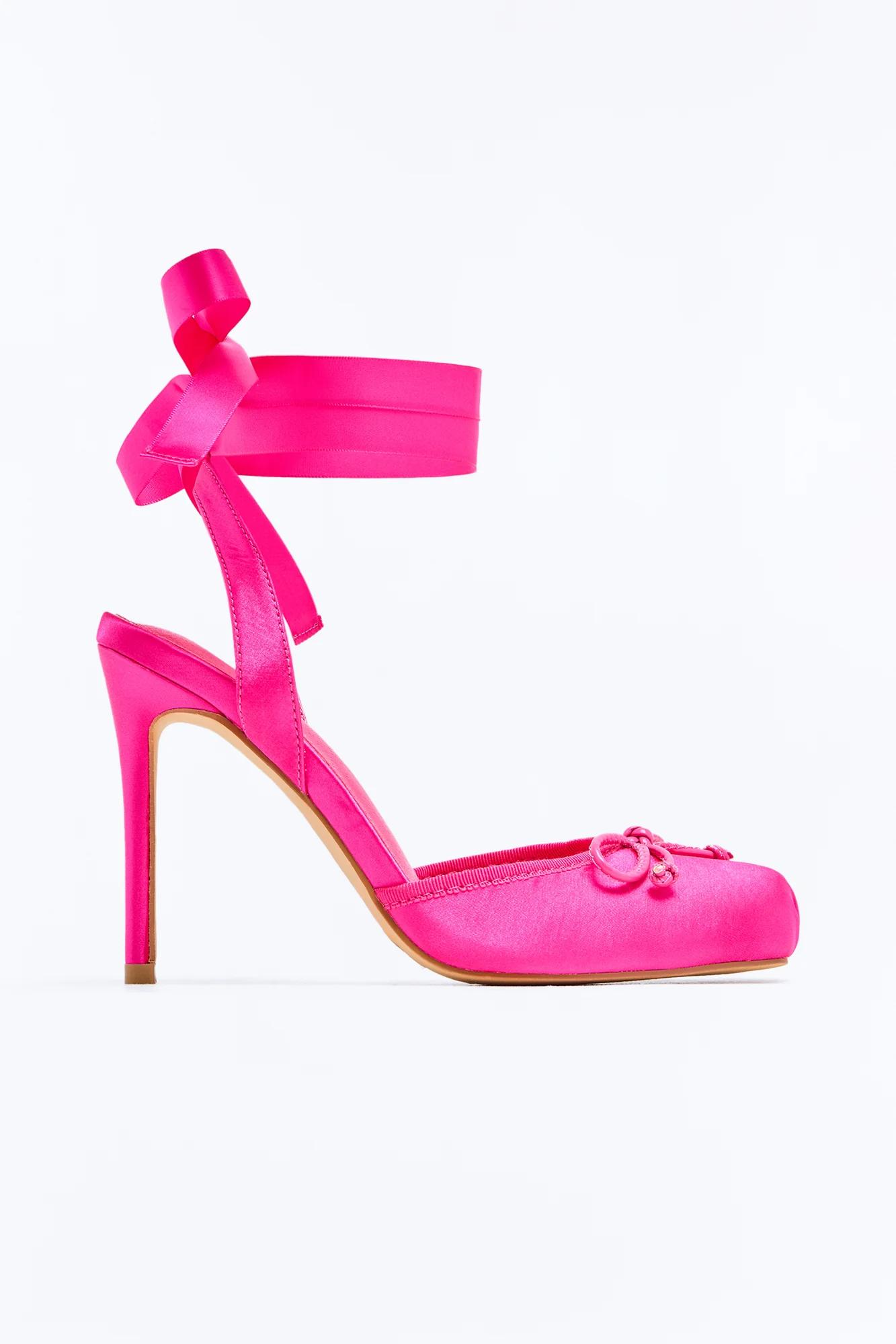 Fuchsia satin stiletto high heel with ankle-tie ribbon and small decorative bow on the pointed toe, against a white background.
