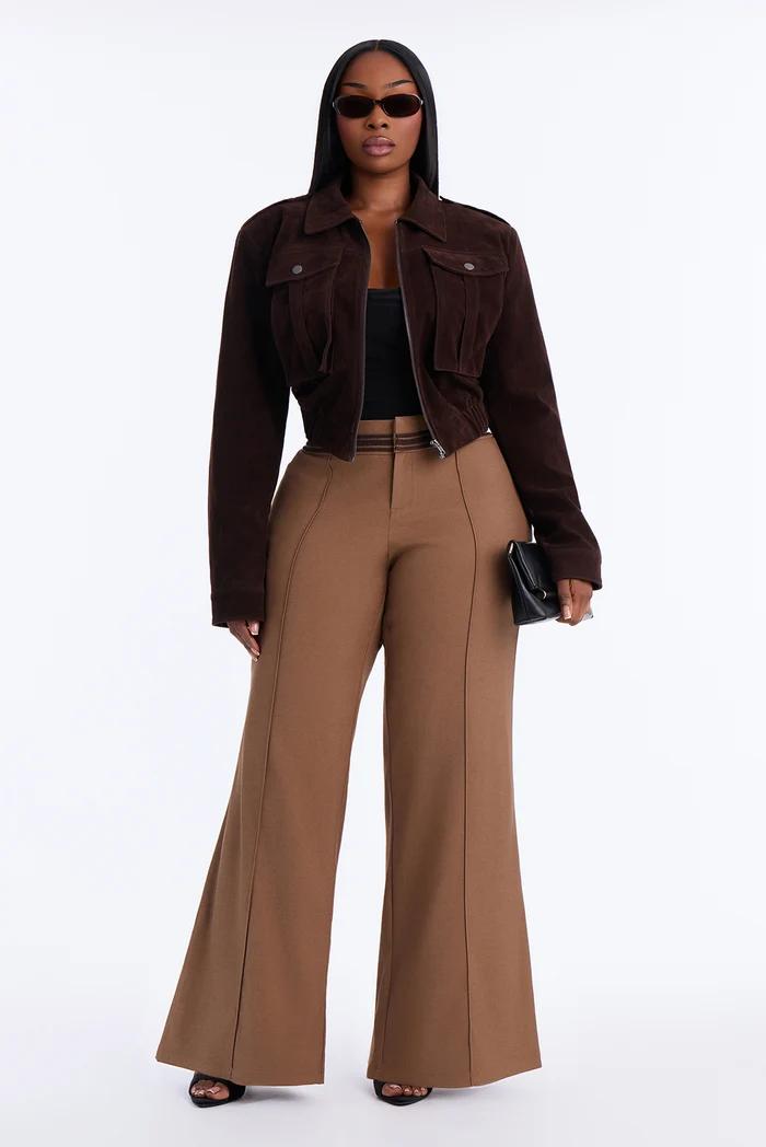 Woman in a dark brown cropped jacket and tan high-waisted wide-leg trousers.