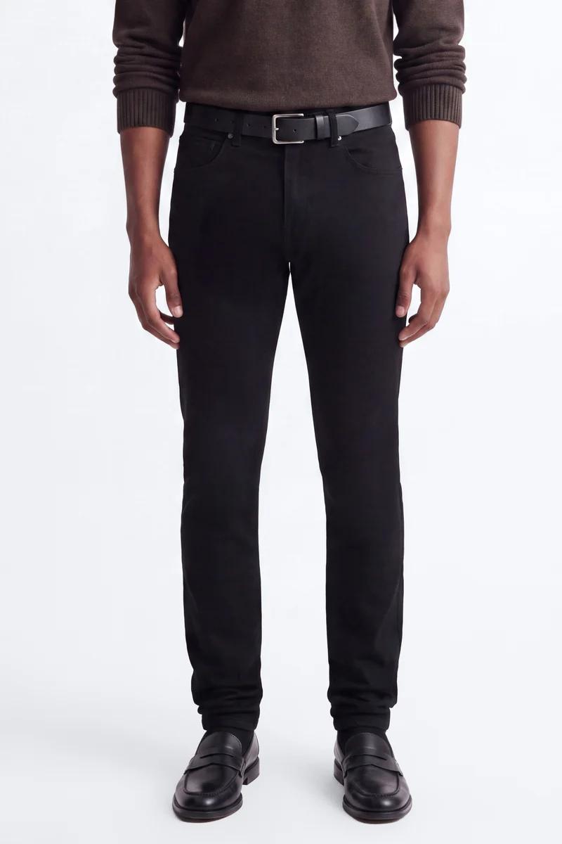 Man models a stylish brown sweater, black jeans, and leather loafers, ideal for versatile men's casual wear.