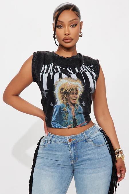 Woman in dark acid wash Tina Turner graphic crop top and light wash fringe denim jeans, showcasing edgy concert tee fashion.