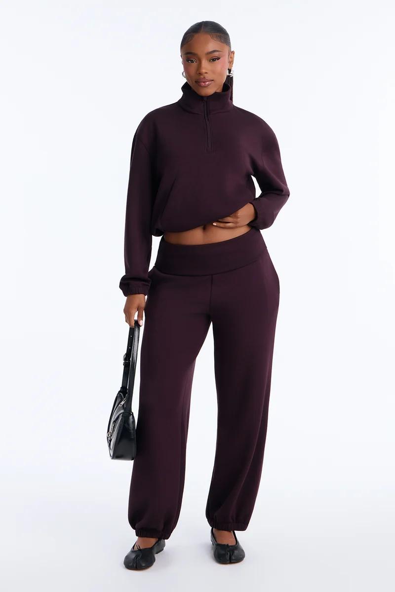 Woman in a dark burgundy half-zip pullover sweatshirt and matching sweatpants set.