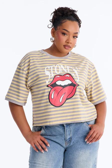 Woman in a yellow and grey striped t-shirt featuring white 'STONES' text and red Rolling Stones lips logo, light blue jeans.