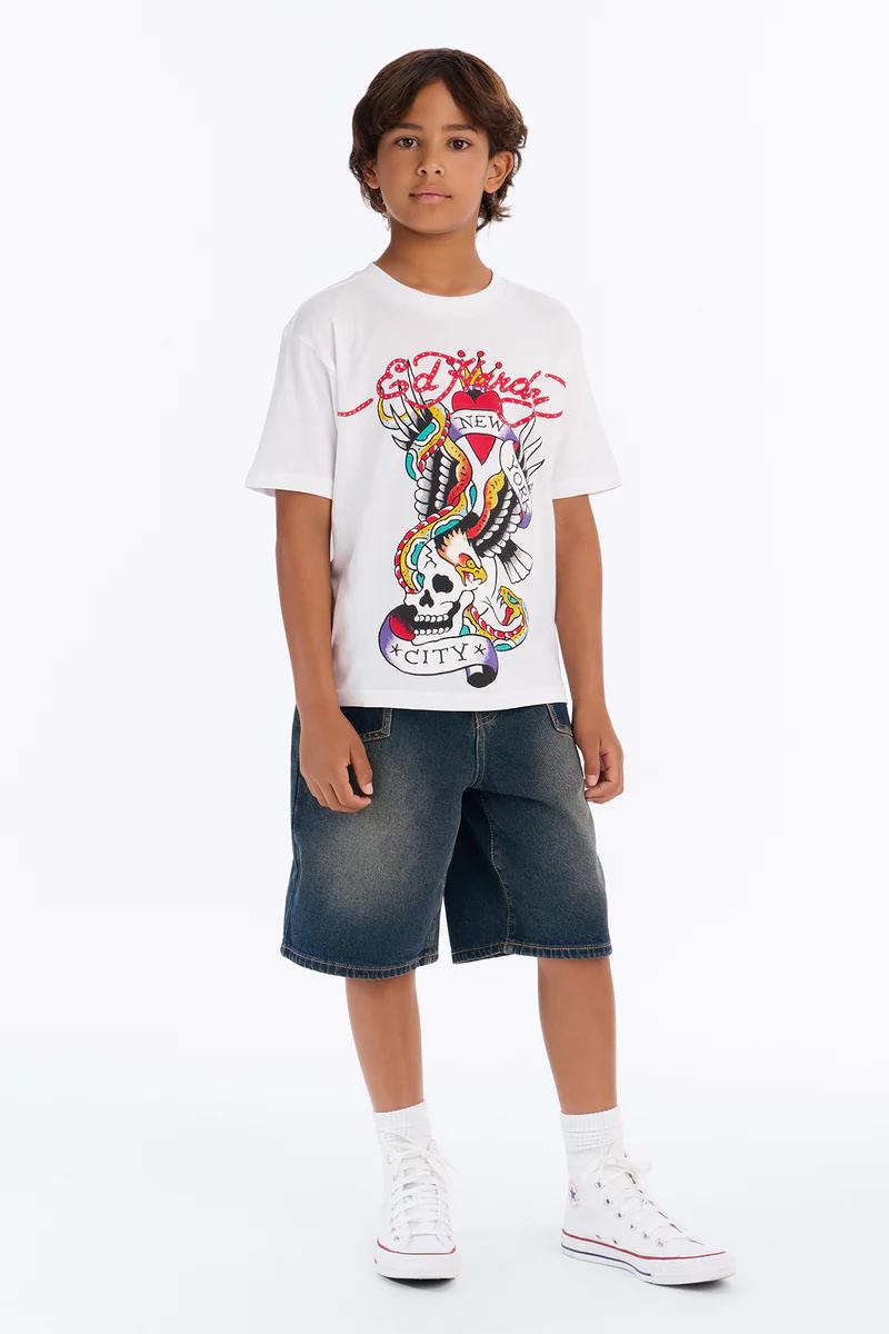 Boy in Ed Hardy white graphic t-shirt with eagle & snake, denim shorts, and white sneakers. Kids' streetwear fashion.