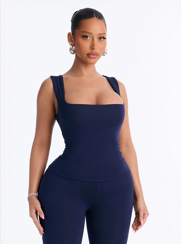 Model wears a sleek navy blue square-neck tank top and matching leggings from the new activewear collection against a white background.