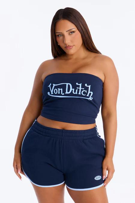 Woman with long dark hair wearing a navy blue strapless 'Von Dutch' top and matching shorts with light blue trim, against a white background.