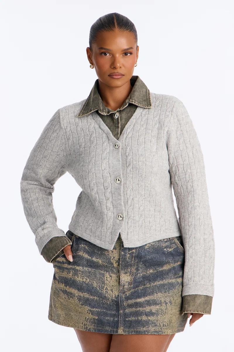 Grey cable knit button-front cardigan sweater layered over a green denim shirt.
