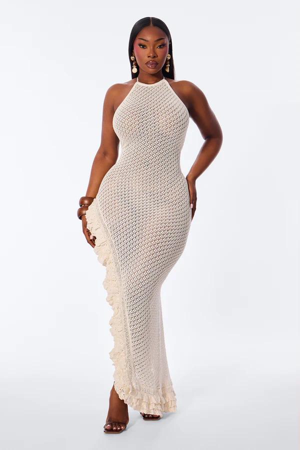 Woman in a fitted, full-length cream intricate crochet halter maxi dress with cascading ruffles, showcasing elegant summer fashion.