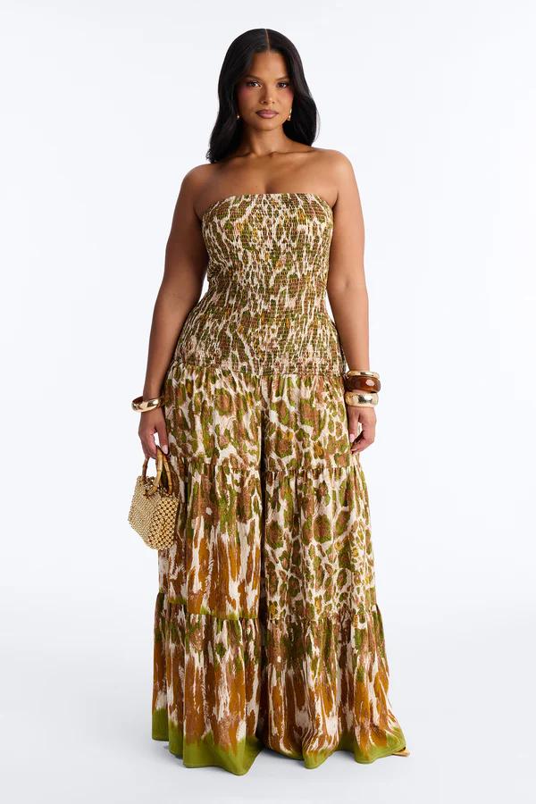 Mujer con mono palabra de honor fruncido, estampado animal oliva-marrón, con bolso de paja. Moda resort ideal.